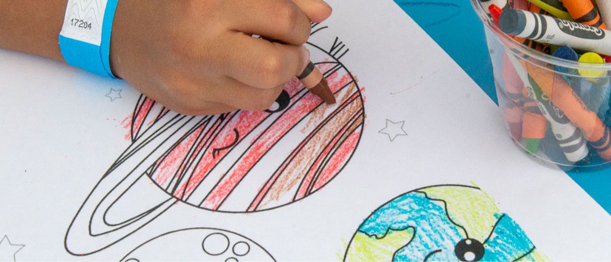 A person coloring a planet with a brown crayon.