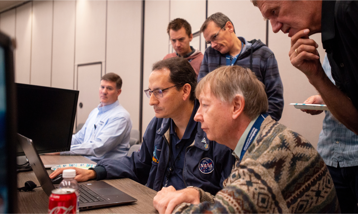 Members of the AWE science team gathered around a computer monitor indoors.