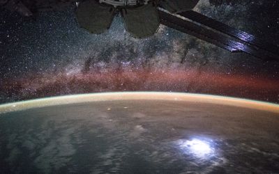 An image taken from the International Space Station shows orange swaths of airglow hovering in Earth’s atmosphere.