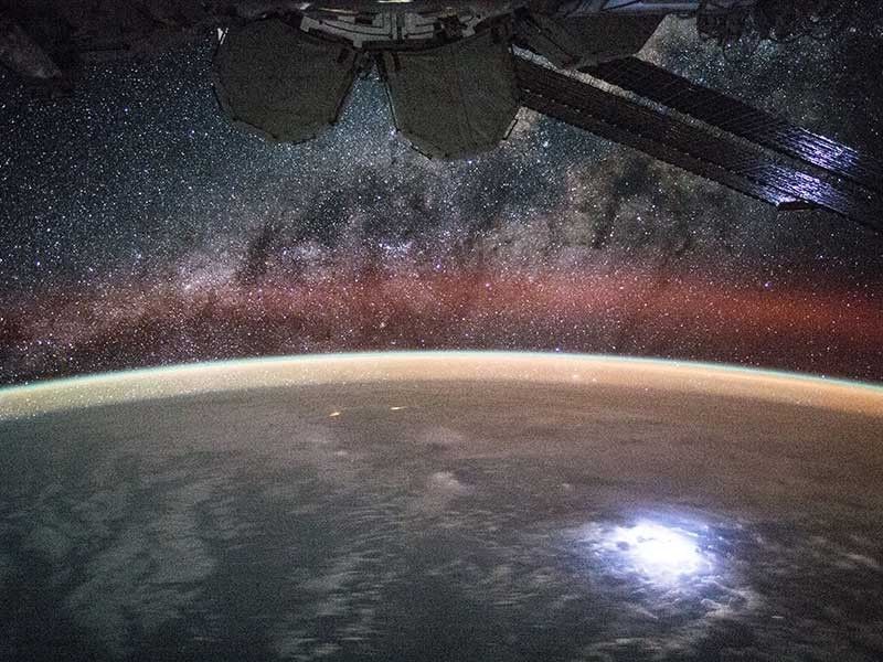 Image taken from the International Space Station showing orange swaths of airglow above Earth's atmosphere.