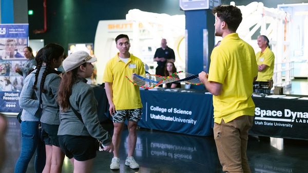 USU Physics scholars Anh Phan, center, and Joe Pigott, right, use a model made from wooden skewers and gumdrops to demonstrate atmospheric gravity waves to young guests at NASA's Kennedy Space Center in Florida. (Photo Credit: SDL/Allison Bills)